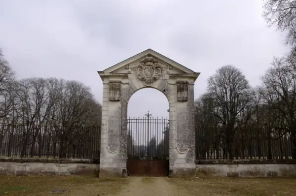 Portail monumental menant au **château de Richelieu**, avec une grille en fer forgé et des arbres dénudés en arrière-plan.