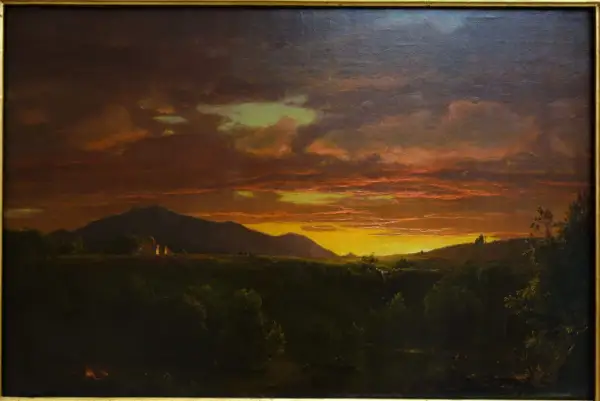 Un paysage de crépuscule, baigné de lumières orangées et dorées, évoquant la beauté mélancolique d'un crépuscule victor hugo. Des montagnes se dressent à l'horizon, tandis que des lumières douces émanent de quelques habitations.