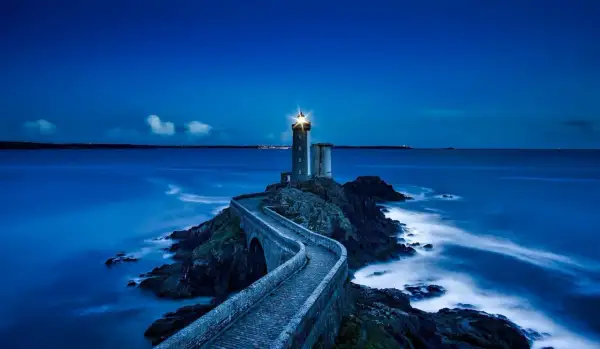 Un phare solitaire, tel un gardien des mers, éclaire la nuit. Son faisceau puissant guide les navires, rappelant les vers de Baudelaire sur la beauté sombre de l'océan.