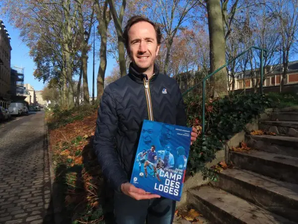 Un homme tient un livre intitulé "Dans l'histoire du Camp des Loges", avec des images de football sur la couverture.